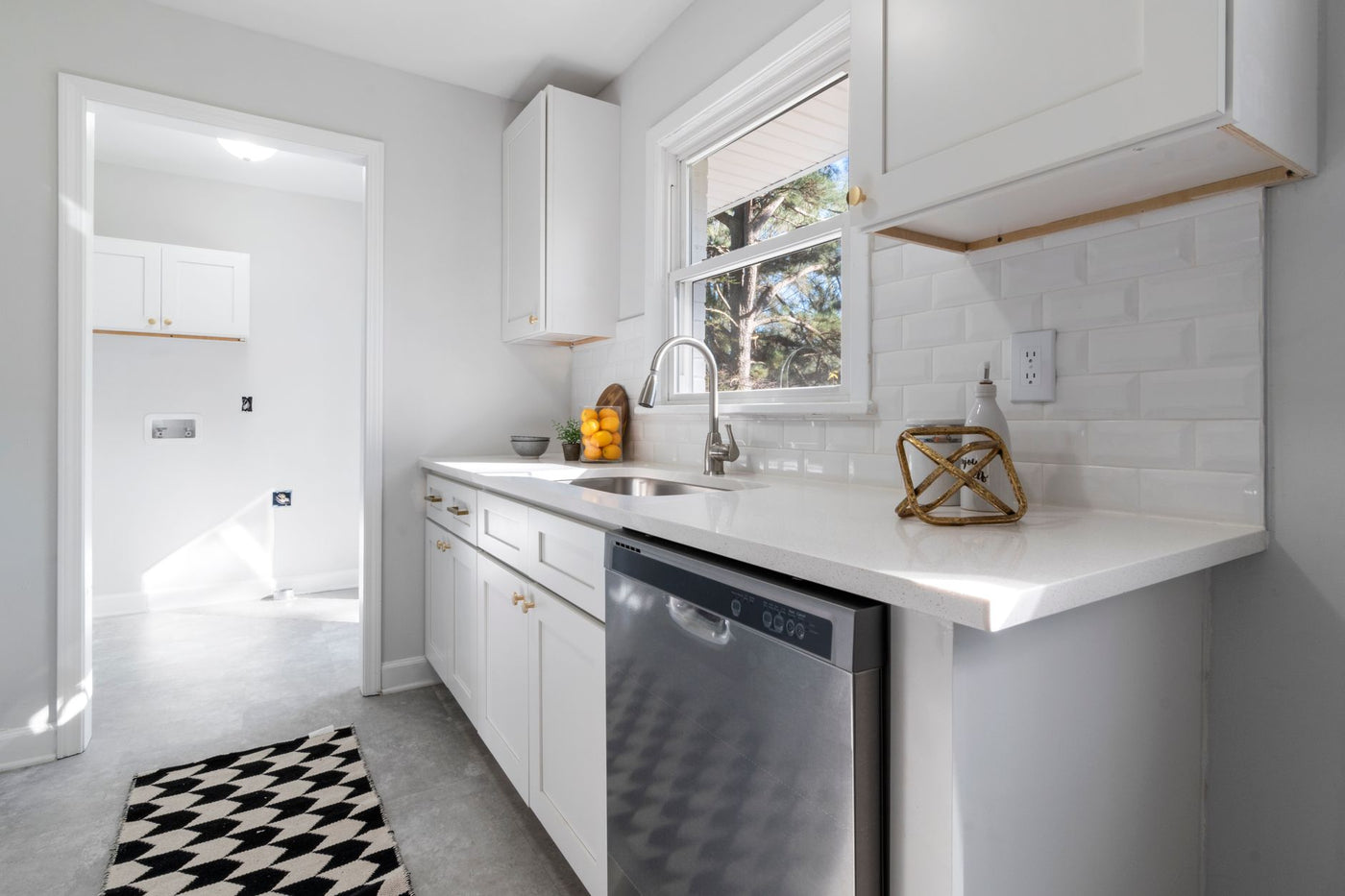 Bright and modern white kitchen interior featuring stainless steel appliances and stylish decor.