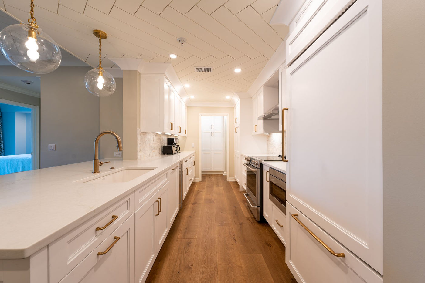 Bright and spacious modern white kitchen with gold accents and elegant lighting, showcasing contemporary design details.
