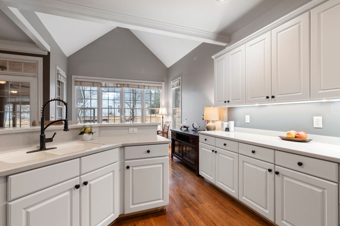 Spacious modern kitchen with white cabinets and large windows providing natural light.